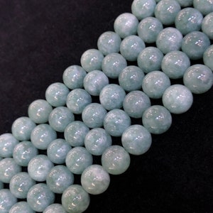 May include: A strand of light green jade beads. The beads are round and smooth, and they have a slightly translucent appearance.