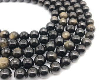 May include: A strand of black and gold beads. The beads are round and have a smooth, polished finish. The gold flecks in the beads are visible and create a shimmering effect.