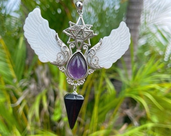 May include: A silver pendant with a purple amethyst stone, a black crystal point, and two white wings. The pendant is designed with a geometric star shape.