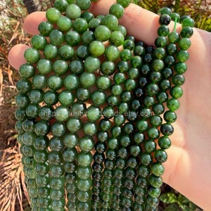 Puede incluir: Hileras de cuentas de jade verde pulidas y redondas. Las cuentas varían en tamaño y tono, de verde claro a oscuro. Las cuentas están ensartadas, y la imagen incluye el texto "https://prettybeadsfinds.etsy.com."