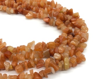 May include: A strand of orange and brown chip-shaped gemstone beads. The beads are irregular in shape and size, and have a natural, polished finish.