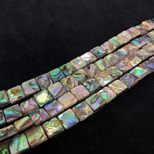 Peut inclure: Un brin de perles carrées en nacre d'ormeau irisées. Les perles sont un mélange de vert, de brun et de blanc.