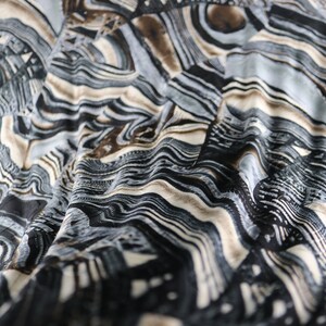 May include: Abstract fabric with a wavy, layered pattern in shades of black, brown, and white.