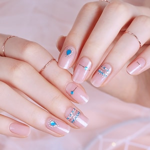 May include: Close-up of hands with light pink nail polish and blue and silver glitter nail art designs.