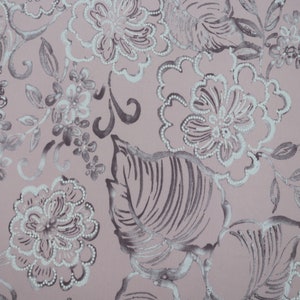 May include: A pink fabric with a white and gray floral pattern. The flowers are stylized and have a delicate, almost lace-like appearance. The background is a soft pink.