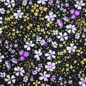 May include: Black fabric with a small floral pattern. The flowers are white with purple centers and yellow centers.