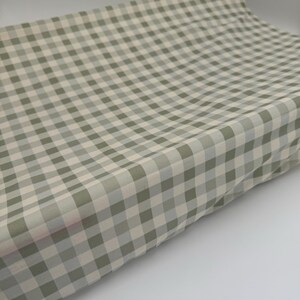 May include: A green and white gingham fabric with a subtle sheen. The fabric is folded and appears to be soft and lightweight.