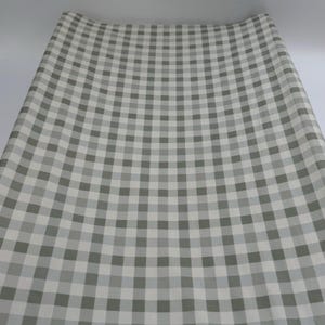 May include: A roll of white and grey gingham wrapping paper. The paper has a checkered pattern.
