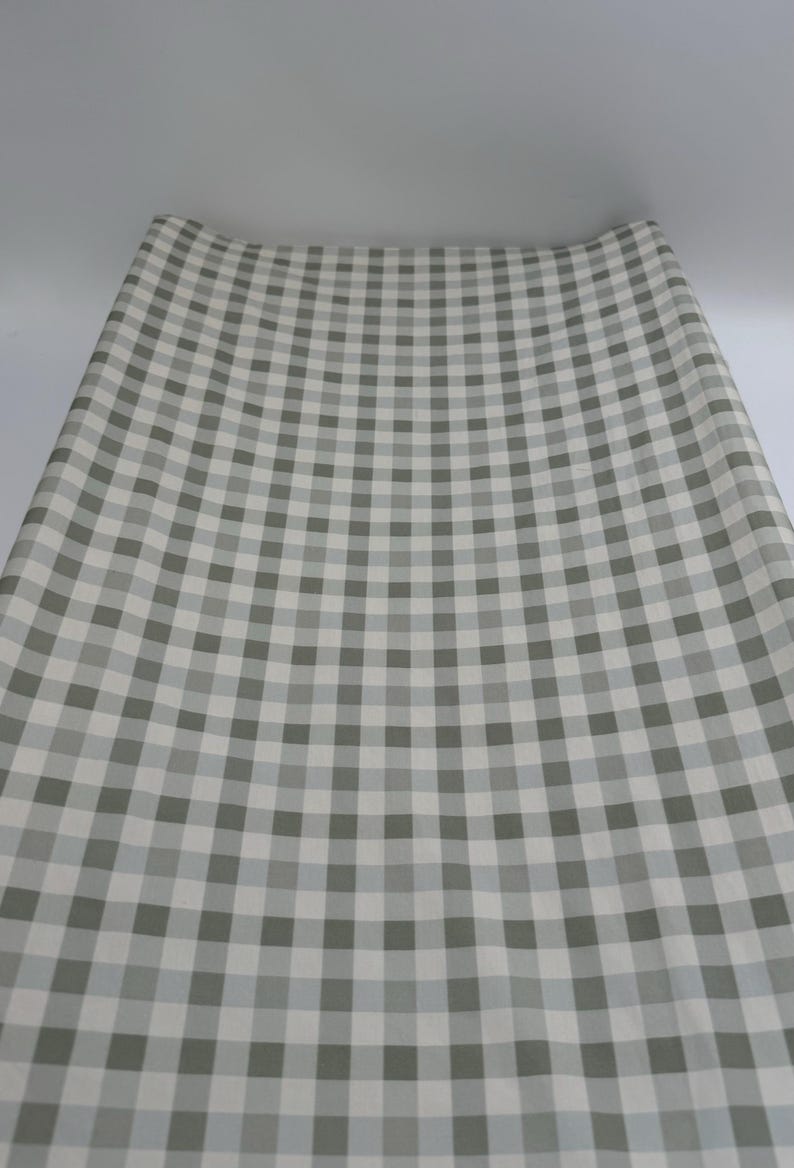 May include: A roll of white and grey gingham wrapping paper. The paper has a checkered pattern.