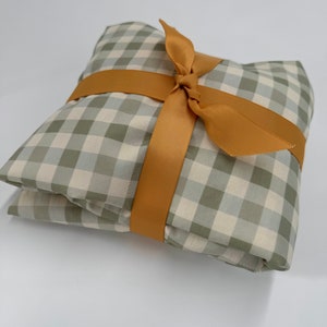 May include: A green and white gingham fabric gift wrapped with a golden ribbon.