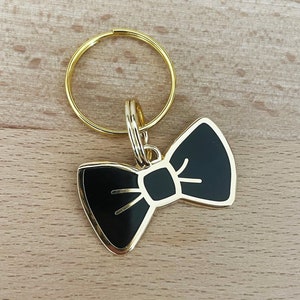 May include: A gold-colored key chain with a black bow tie charm.