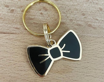 May include: A gold-colored key chain with a black bow tie charm.