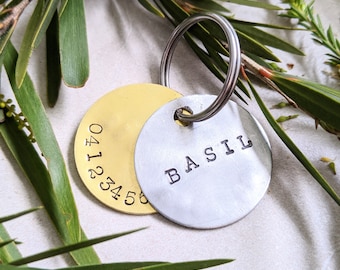 May include: A gold and silver metal tag with a key ring. The gold tag has the numbers 04123456 engraved on it. The silver tag has the word "BASIL" engraved on it.