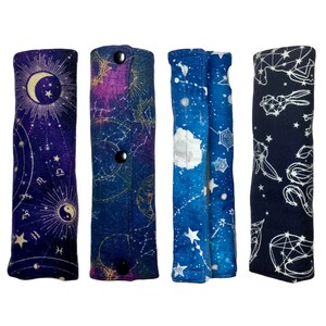 May include: Four fabric pencil cases with a celestial theme. Each case features a different constellation pattern in shades of blue, purple, and white on a dark background. The cases have a button closure.