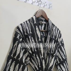 Könnte beinhalten: Eine schwarz-weiße Robe mit Fischdruck und weißen Punkten. Die Robe hat einen Bindegürtel und 3/4 Ärmel.