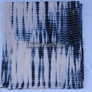 May include: A white and blue tie-dye fabric with a repeating pattern. The fabric is soft and lightweight, making it perfect for scarves, clothing, or home decor.