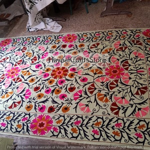Peut inclure: Un tissu de coton blanc avec un motif de broderie florale. La broderie présente des fleurs roses, orange et noires avec des tiges vertes. Le tissu est un style de broderie traditionnel.