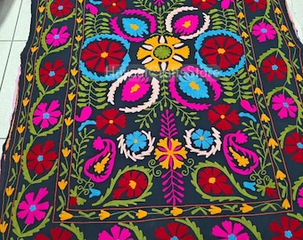 May include: A black textile featuring vibrant, multi-colored floral and paisley embroidery. The design includes large red, hot pink, yellow, and light blue flower motifs arranged in a symmetrical pattern with green leafy vines and stems.