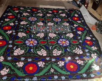May include: A large rectangular black textile featuring a repeating floral pattern in red, light pink, blue, and green. The design includes circular flower motifs and leafy vines. The text HayaatCraftsStore is printed in the center of the fabric.