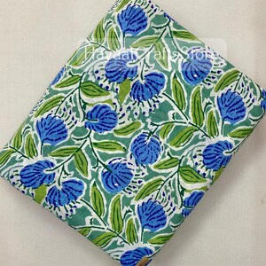 May include: A green and white fabric with a blue floral print. The fabric has a repeating pattern of blue flowers and green leaves.