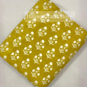 May include: Yellow fabric with a white floral print. The fabric has a subtle texture and a soft, muted yellow colour.