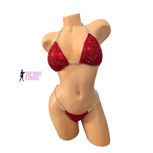 May include: Red competition bikini with silver rhinestones. The top and bottom are connected by a silver chain.