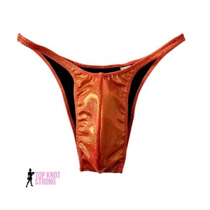 May include: A red and gold shimmery posing suit with a low cut and a high leg.