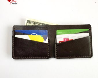 May include: A brown leather wallet with multiple card slots and a billfold. The wallet is open and has a few cards and a dollar bill inside.