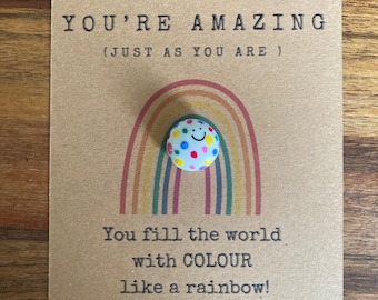 May include: A card with a rainbow and a smiley face button that says "Remember... You're amazing (Just as you are). You fill the world with color like a rainbow!" and the website www.palsinyourpocket.com