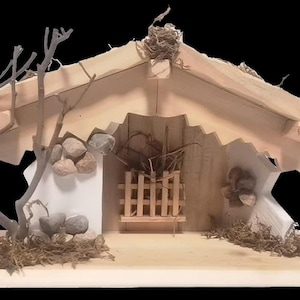 Peut inclure: Une crèche de Noël en bois avec une petite étable simple avec une clôture en bois et un toit de chaume. L'étable est décorée de petites pierres et de brindilles.