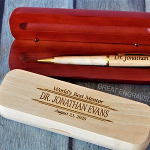 May include: A wooden pen and case set. The pen is light-colored with gold accents and the inscription "Dr. Jonathan." The case is open, revealing a red interior. The closed case is engraved with "World's Best Mentor DR. JONATHAN EVANS August 23, 2020."