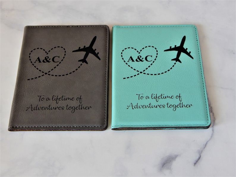 May include: Two passport holders, one gray and one turquoise, with the initials "A&C" and a plane flying in a heart shape. The text "To a lifetime of Adventures together" is engraved on both holders.