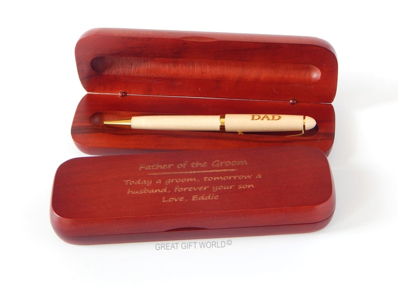 May include: A wooden pen with gold accents and the word "DAD" engraved on the barrel, presented in an open, dark-stained wooden case. The case lid has an inscription: "Father of the Groom...Love, Eddie."