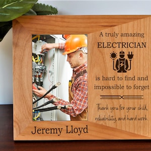 May include: A wooden picture frame with a photo of an electrician working on electrical wiring. The frame includes the text "A truly amazing ELECTRICIAN is hard to find and impossible to forget." The name "Jeremy Lloyd" is also displayed.