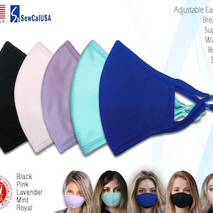 Op de afbeelding: Vijf gezichtsmaskers in verschillende kleuren: zwart, roze, lavendel, mint en koninklijk blauw. De maskers zijn gemaakt van zacht, ademend materiaal en hebben verstelbare oorlussen. De tekst "SewCalUSA" en "Made in U.S.A." is zichtbaar in de linkerbovenhoek van de afbeelding. De tekst "Adjustable Ear Loops", "Breathable", "Super Soft", "Washable", "Reusable" en "3 Layers" is zichtbaar in de rechterbovenhoek van de afbeelding. De tekst "Black", "Pink", "Lavender", "Mint" en "Royal" is zichtbaar in de linkerbenedenhoek van de afbeelding. De tekst "NEW ARRIVAL" is zichtbaar in een rode cirkel in de linkerbenedenhoek van de afbeelding.