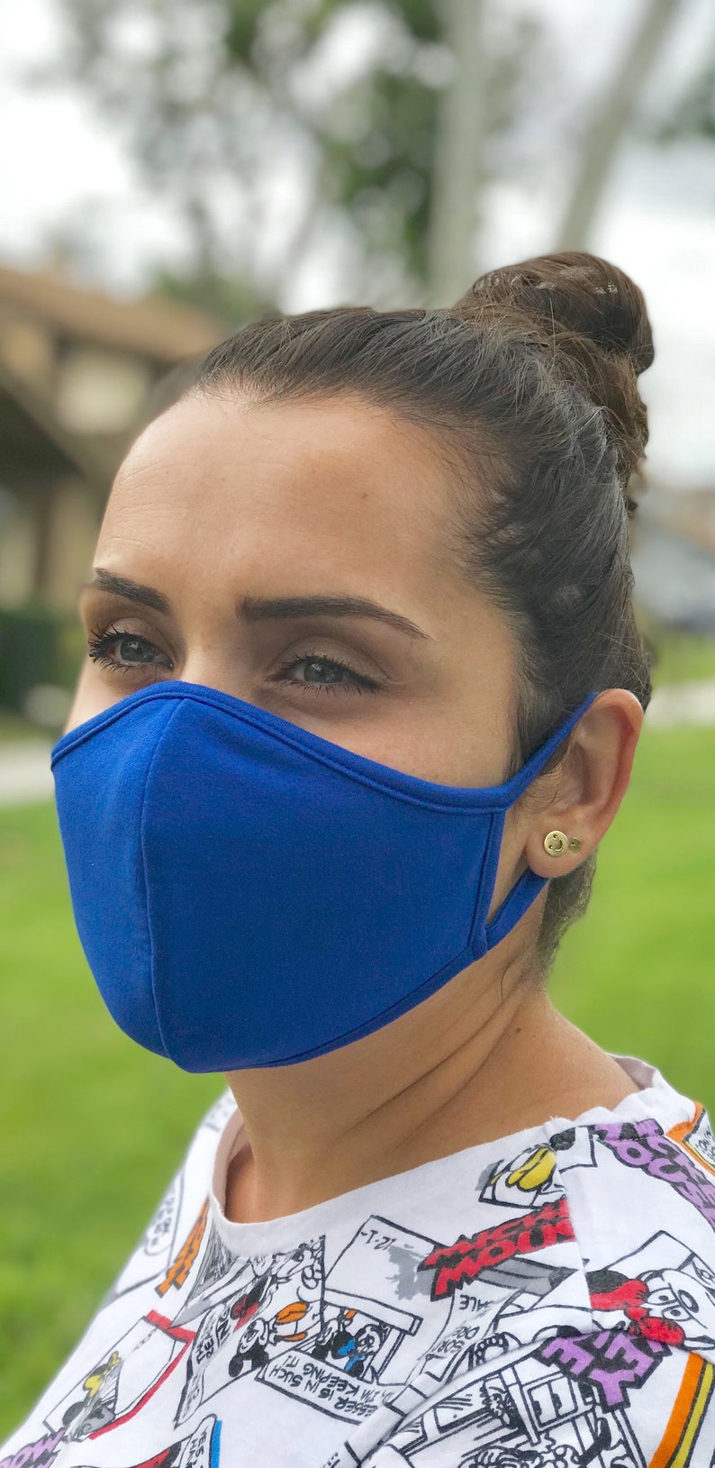Op de afbeelding: Een persoon draagt ​​een felblauw mondkapje. Het masker is gemaakt van een zachte, comfortabele stof. De persoon draagt ​​een wit shirt met een cartoonprint.