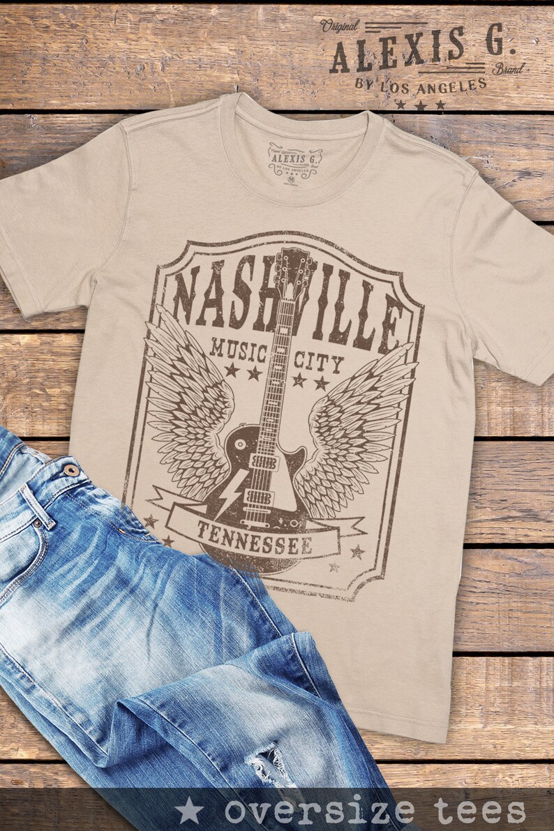May include: A beige t-shirt featuring a vintage-style graphic of a guitar with wings and the text "Nashville Music City Tennessee".