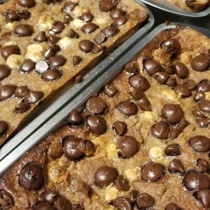May include: Close-up of a baking dish filled with a sweet bread pudding topped with chocolate chips. The pudding is a light brown color and the chocolate chips are scattered evenly across the top.