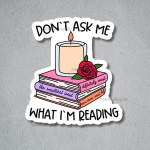 Puede incluir: Una pegatina con el texto "DON'T ASK ME WHAT I'M READING". Presenta una vela en un vaso, una rosa roja y una pila de libros con los t&iacute;tulos "the smuttiest smut", "definitely smut" y "even more smut lol".