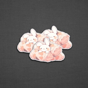May include: Three white bunny stickers with pink and white blankets. The bunnies are peeking out from the blankets.