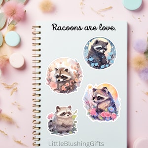 Puede incluir: Cuatro pegatinas redondas con adorables mapaches de dibujos animados con flores y una luna. Las pegatinas est&aacute;n en una libreta azul con el texto "Raccoons are love." y "LittleBlushingGifts".