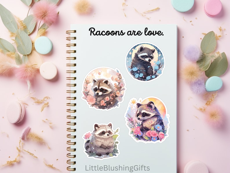Puede incluir: Cuatro pegatinas redondas con adorables mapaches de dibujos animados con flores y una luna. Las pegatinas est&aacute;n en una libreta azul con el texto "Raccoons are love." y "LittleBlushingGifts".
