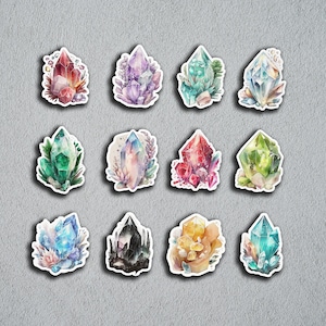 Può includere: Dodici illustrazioni ad acquerello di diversi cristalli e pietre preziose. Ogni illustrazione presenta una forma e un colore di cristallo unici, circondati da delicati elementi floreali.