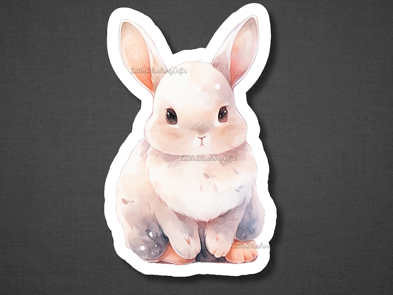May include: A white watercolour bunny with brown eyes and a pink nose. The bunny is sitting with its paws tucked under its body. The background is a soft, watercolour wash of blue and pink.
