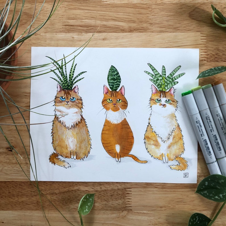 以下が含まれることがあります： 頭から植物が生えている猫の水彩画3点。猫はすべて直立して座っており、毛の色が異なります。植物は緑色で、さまざまな質感があります。