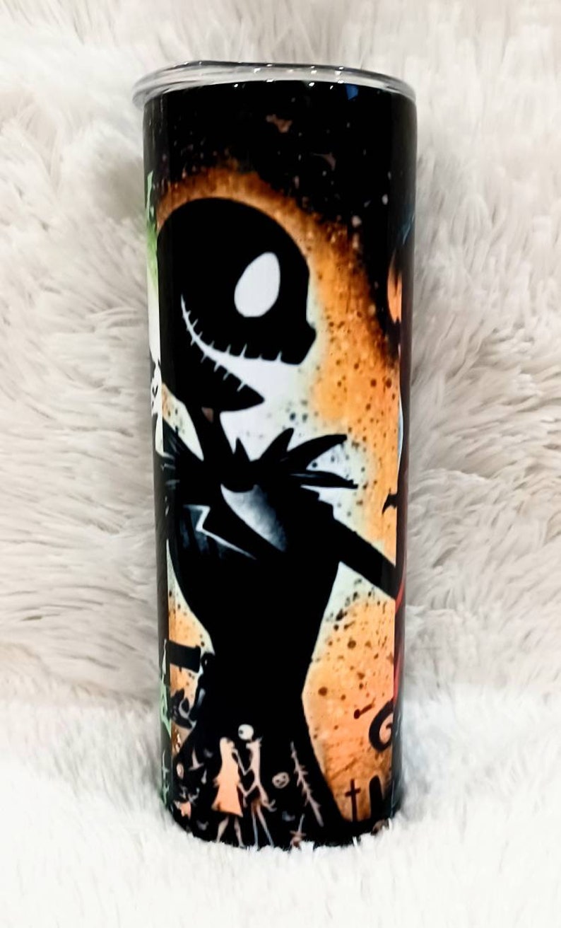 Puede incluir: Un vaso cil&iacute;ndrico con un dise&ntilde;o de Jack Skellington de Pesadilla antes de Navidad, sobre un fondo naranja y negro. El dise&ntilde;o incluye otros personajes y elementos de la pel&iacute;cula.