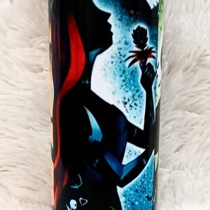 Puede incluir: Un vaso cil&iacute;ndrico con la silueta de una mujer sosteniendo una flor, sobre un fondo azul oscuro y negro con efecto de estrellas. El dise&ntilde;o incluye otros personajes y escenas de una pel&iacute;cula.