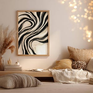 May include: A framed wall art print featuring an abstract design of flowing black and beige brushstrokes that create a swirling, wave-like pattern. The artwork is enclosed in a light-toned wooden frame, showcasing a high-contrast composition.