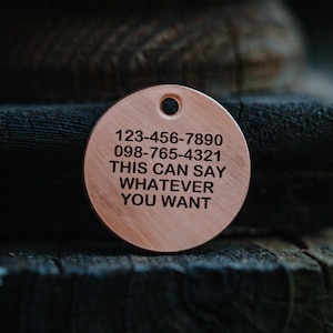 May include: A round copper tag with two phone numbers and the text "THIS CAN SAY WHATEVER YOU WANT".