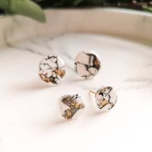 Könnte beinhalten: Drei Paar weiße und schwarze Marmor-Ohrstecker mit goldenen Flocken. Die Ohrringe sind rund und haben ein schlichtes Design.